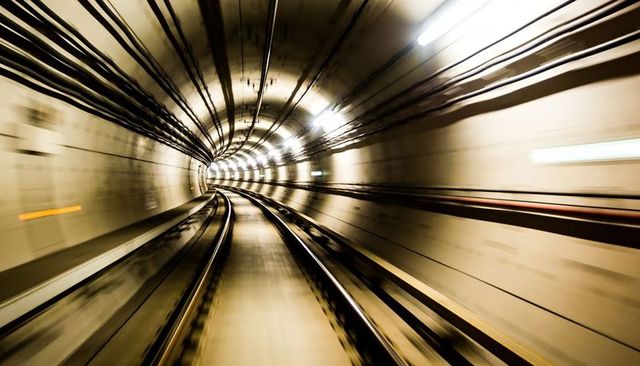 High-speed curving subway tunnel racing toward vanishing point with twin tracks and motion blur
