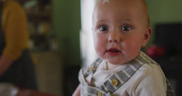 Portrait of happy caucasian baby looking at camera in kitchen. homesteading, healthy lifestyle on organic farm in the countryside.