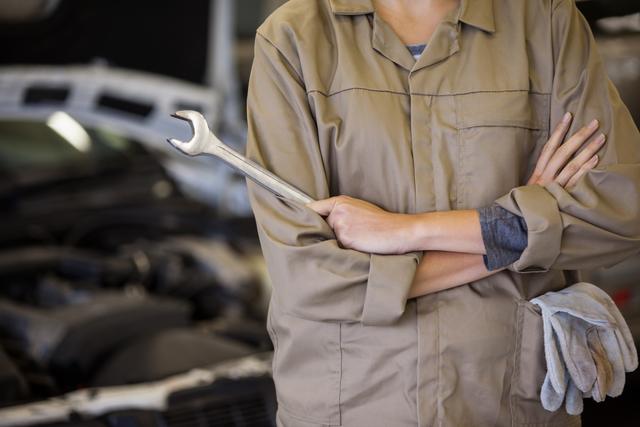 Female mechanic with arms crossed and spanner at the repair garage