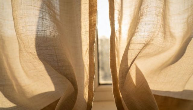 Backlit beige linen curtains showing sheer texture and warm sunlight through window