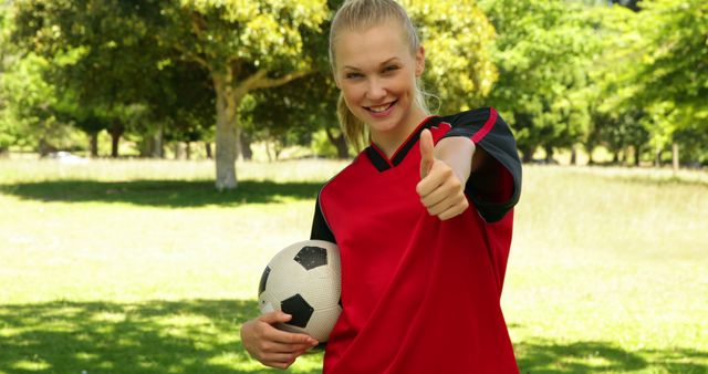 Blonde football player smiling and giving thumbs up to camera on a sunny day