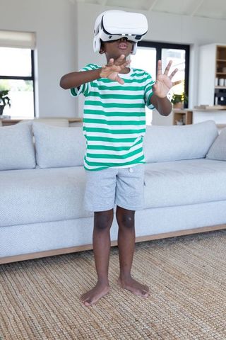 African american boy exploring virtual reality at home wearing vr headset reaching forward