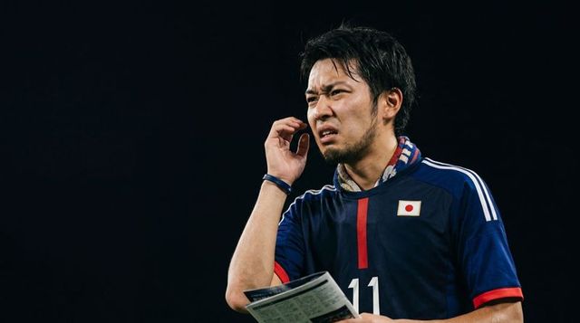 Japan soccer player reviewing notes and touching ear during night match