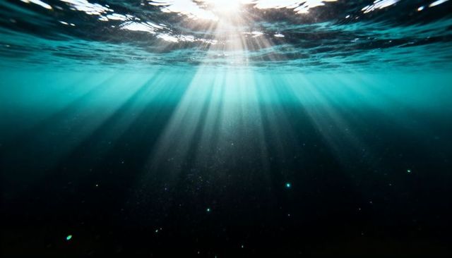 Sunlight streaming through ocean surface into deep turquoise water with dramatic rays