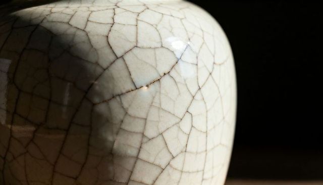 Crackle-glazed ceramic vase close-up showing craquelure texture and dramatic light