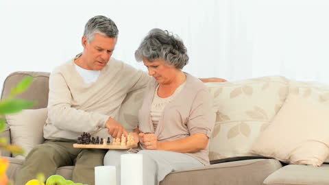 Senior Couple Strategically Playing Chess on Couch