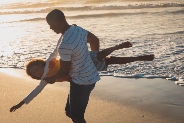 Father and son enjoying playful moments on the beach during sunset. Perfect for promoting family vacations, summer activities, and outdoor bonding experiences. Ideal for use in travel brochures, family-oriented advertisements, and lifestyle blogs.
