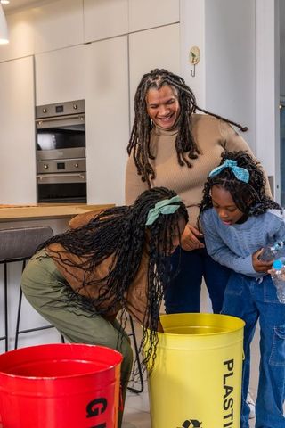 African american mother teaching children recycling at modern kitchen island