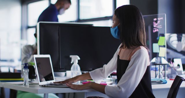 Woman Wearing Mask Working on Laptop in Modern Office - Download Free Stock Images Pikwizard.com