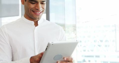 Smiling businessman using tablet in bright office environment