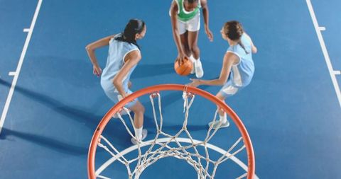 Diverse female basketball players competing under hoop