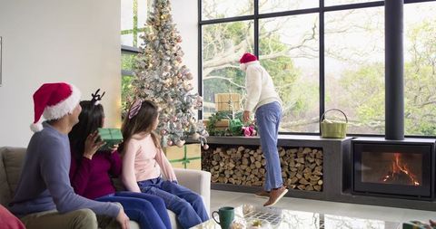 Diverse family celebrating Christmas in cozy modern living room with fireplace and gifts