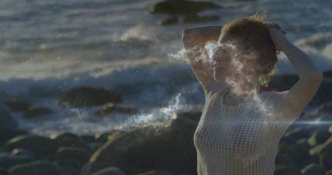 Cosmic double exposure woman on rocky shore at sunrise nebula overlay, fashion lifestyle