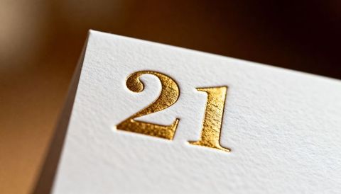Gold foil embossed 21 on textured white cardstock macro luxury detail