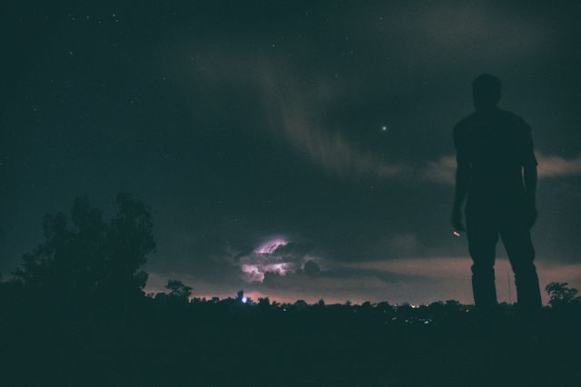 Person Watching Night Sky with Lightning Storm in Distance - Download Free Stock Photos Pikwizard.com