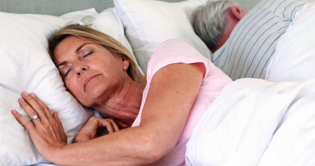 Senior couple sleeping back to back on bed in bed room