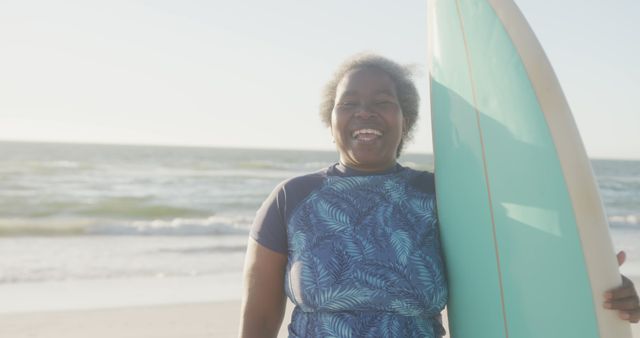 Smiling Senior African American Woman Holding Surfboard on Beach - Download Free Stock Images Pikwizard.com