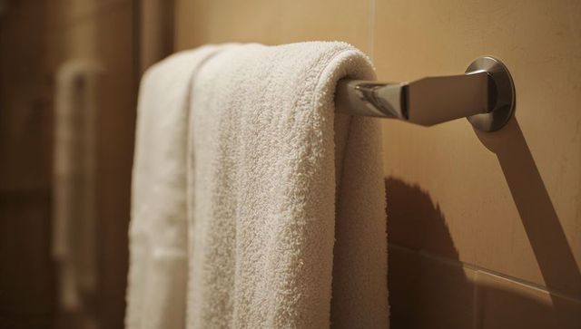 Hanging cream terry towel on polished chrome towel bar, plush texture and warm beige tones