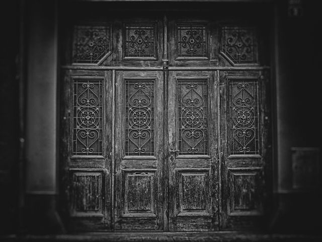 This image showcases a beautifully crafted vintage wooden door with an ornate iron grill work, captured in black and white. This image can be used in historical projects, interior design magazines, architectural portfolios, or as a striking visual for art and photography collections that emphasize old-world charm and craftsmanship.