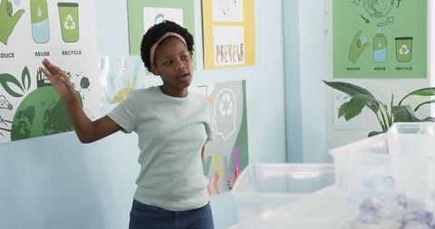 Youth presenting classroom recycling lesson with clear sorting bins and eco posters