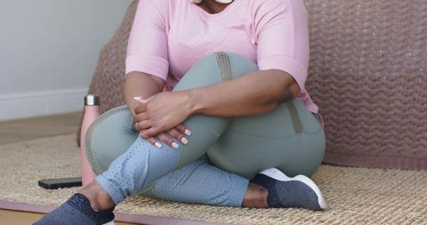 African american woman sitting cross-legged practicing mindfulness and relaxation in living room