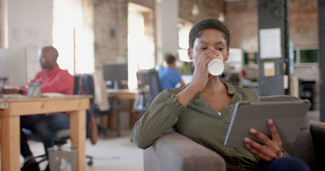 Young Professional Drinking Coffee While Using Tablet in Modern Office - Download Free Stock Images Pikwizard.com