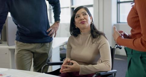 Inclusive workplace collaboration with woman in wheelchair leading diverse team