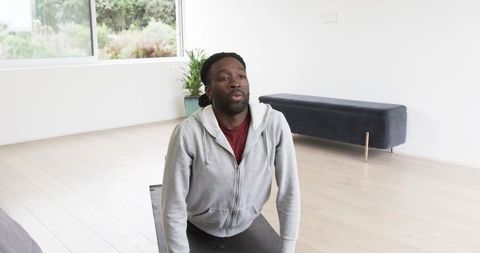 African American man stretching in minimalist sunlit living room practicing yoga backbend