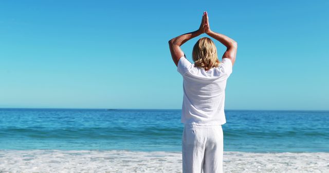 Rear view of man performing yoga at beach on a sunny day 4k