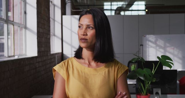 Portrait of biracial businesswoman looking ahead then shifting gaze to camera and smiling. business in a modern office.