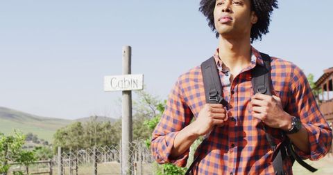 Man Exploring Countryside in Flannel Shirt with Backpack Focused
