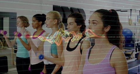 Group Fitness Class Using Wearable Data Visualization While Women Lifting Dumbbells