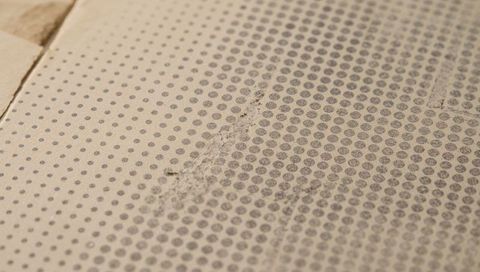 Dotted cement backerboard flooring showing scuffed seam and textured beige underlayment