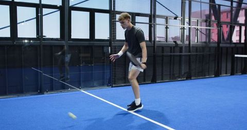Young man practicing padel alone in indoor court