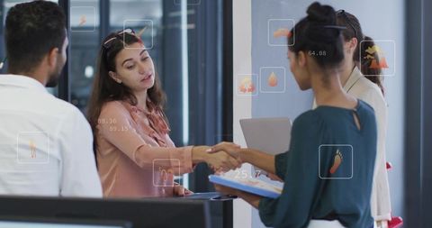 Shaking hands in modern office reception, showing AR icons and colleagues holding clipboard