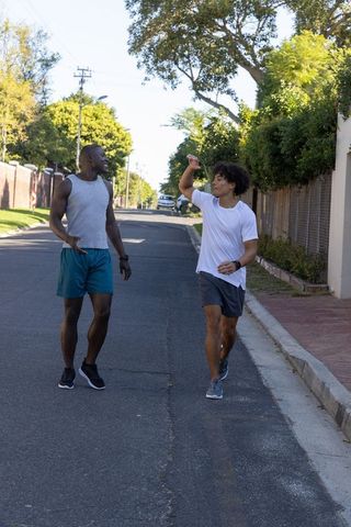Two Male Athletes Jogging with Water Bottle on Suburban Street