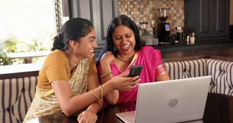 Smiling Indian Mother and Daughter Bonding Over Technology at Home