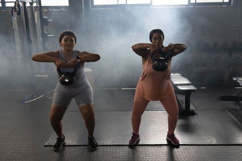 African american women lifting kettlebells together for strength training in industrial gym