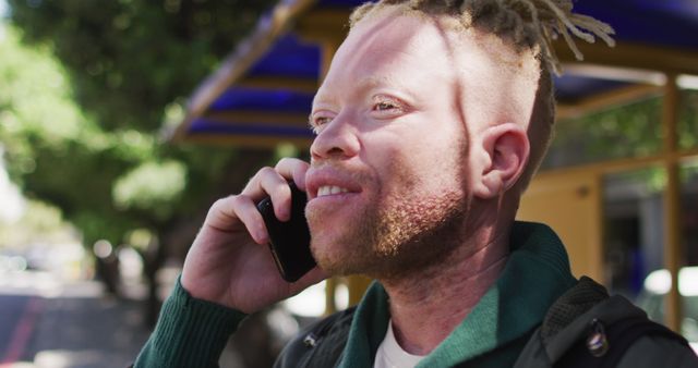 Smiling Albino Man Engaging in Phone Call Outdoors on Sunny Day - Download Free Stock Images Pikwizard.com