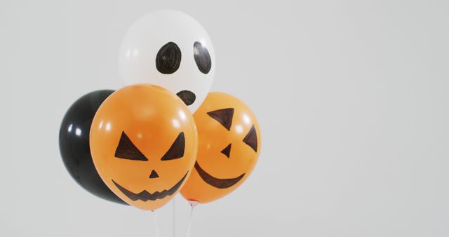 Scary faces printed bunch of halloween balloons against grey background. halloween holiday and celebration concept
