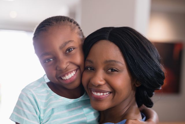 This image captures a joyful moment between a mother and her daughter, both smiling warmly at the camera. Ideal for use in family-oriented advertisements, parenting blogs, or social media posts celebrating family bonds and love. Perfect for illustrating themes of happiness, togetherness, and the special relationship between a parent and child.
