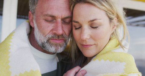 Content mature couple embracing under cozy blanket outdoors
