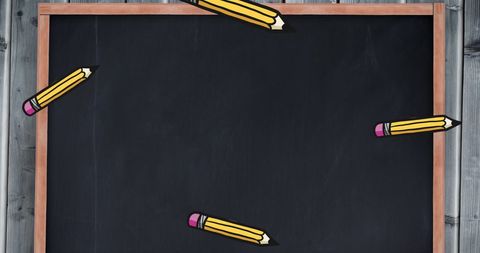 Colorful pencils falling around blank blackboard