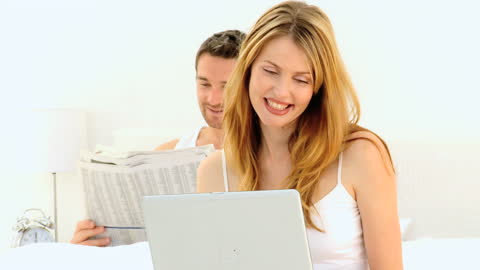 Happy Couple Relaxing with Newspaper and Laptop Wake-Up Scene