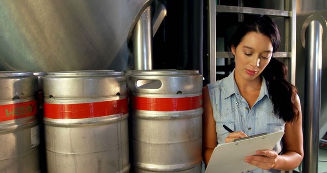 Female Brewery Worker Inspecting Beer Kegs with Clipboard - Download Free Stock Images Pikwizard.com