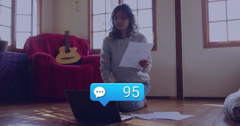 Focused woman analyzing documents on laptop in cozy living room
