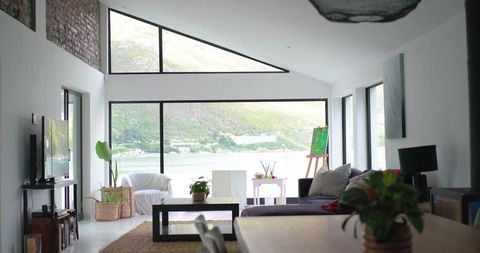 Showcasing modern waterfront living room opening onto floor-to-ceiling glass with sectional sofa and