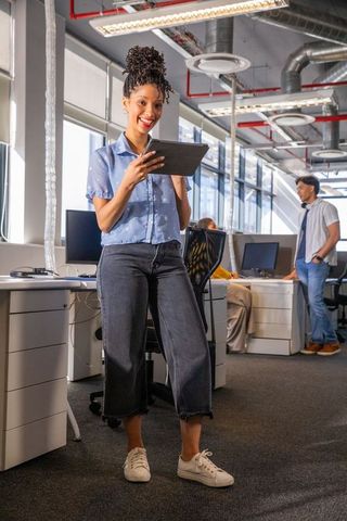 African american woman using tablet in bright modern open office for collaboration