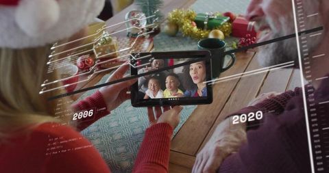 Multigenerational family video calling on tablet celebrating christmas at dining table