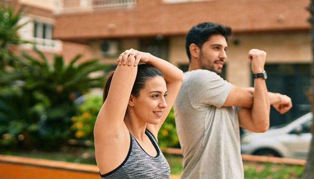 Couple stretching in urban courtyard before outdoor workout for fitness and wellness